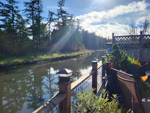 a wooden fence next to a river with a bridge at Charming Cottage by Creek & Ocean in Blaine