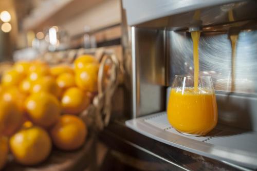 a glass of orange juice is coming out of a machine at Hotel Luis in Fiera di Primiero