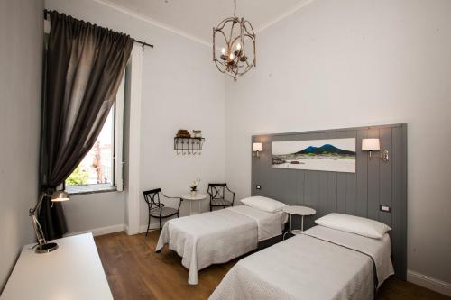 ナポリにあるLargo Donnaregina Homeのベッドルーム1室(ベッド2台、テーブル、シャンデリア付)