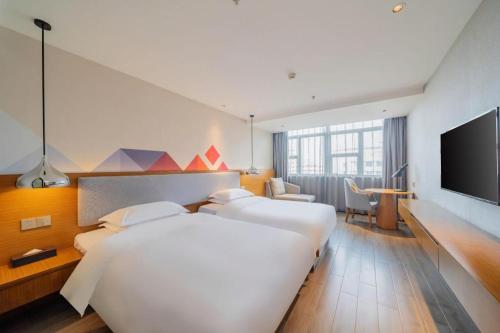 a hotel room with two beds and a flat screen tv at Borrman Hotel Zhanjiang Wuchuan Jinsha Plaza in Zhanjiang