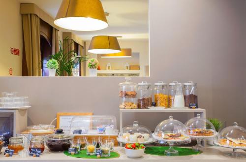 a counter with many bowls of food in glass domes at Hotel Ares Milano in Milan