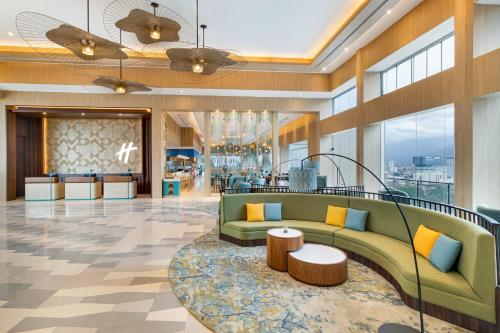 a lobby with a green couch and a table at Holiday Inn Lampung Bukit Randu by IHG in Bandar Lampung