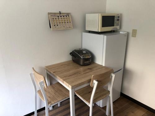 a kitchen with a table with a microwave and a refrigerator at Guesthouse & Kitchen Hace - Vacation STAY 68911v in Iwaki