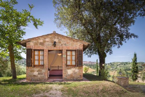 a small stone house in a field with a tree at Agriturismo Palazzo Bandino - Wine cellar, on reservation restaurant and spa in Chianciano Terme