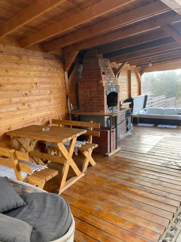 a large wooden deck with a table and a fireplace at 2TowersCabin in Mărişel
