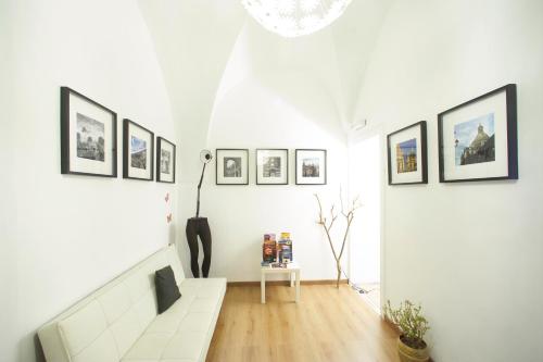 una sala de estar con una pared blanca con cuadros. en B&B Favola Mediterranea, en Catania