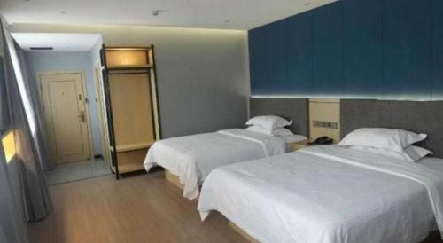 a hotel room with two beds and a mirror at Green Tree Inn Urumqi San'gong Metro Station Exit in Ürümqi