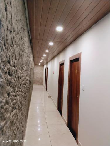 an empty hallway with doors and a stone wall at Hotel Swastik Inn in Gangtok