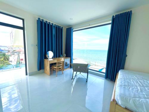 a bedroom with a bed and a desk with a view of the ocean at Hoàng Hôn Nhớ Hotel in Ấp Khánh Phước (1)