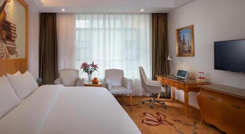 a hotel room with a bed and a desk with a computer at Vienna Hotel Guangdong Zhaoqing Sihui Tianguangxu in Zhaoqing