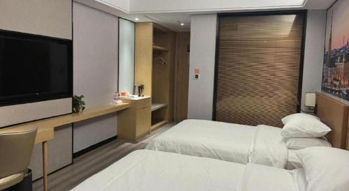 a hotel room with two beds and a flat screen tv at Vienna Hotel Jiangxi Shangrao High-Speed Railway Station in Shangrao
