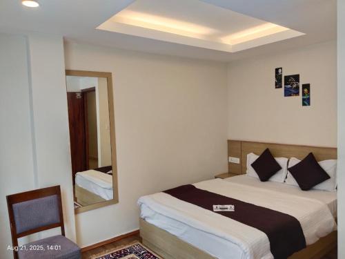 a bedroom with a bed and a mirror and a chair at Hotel Swastik Inn in Gangtok