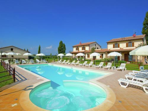 a large swimming pool with chairs and umbrellas at Villa in Cannara with Pool near Assisi in Tordandrea