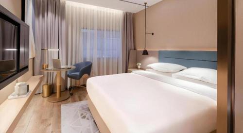a hotel room with a large white bed and a desk at ZMAX Hotels Shenzhen Lianhuacun Metro Station in Shenzhen