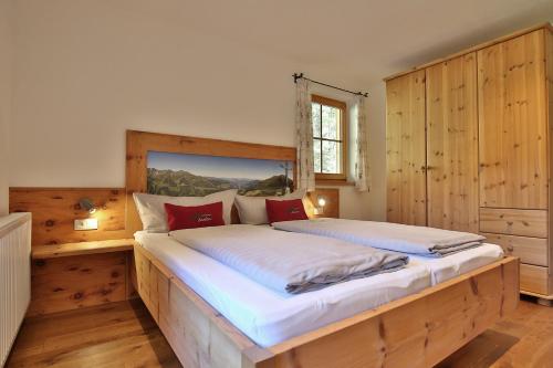 a bedroom with a large wooden bed with red pillows at Alpboden in Auffach