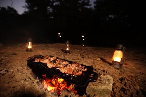 a grill with food on top of a fire at Kumana Under Canvas in Panama
