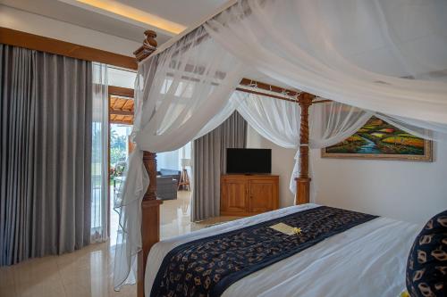 a bedroom with a canopy bed and a television at d'Bulih Villa Ubud in Ubud