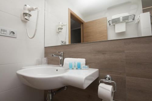 a bathroom with a sink, mirror, and bathtub at Hotel Perla in Benidorm