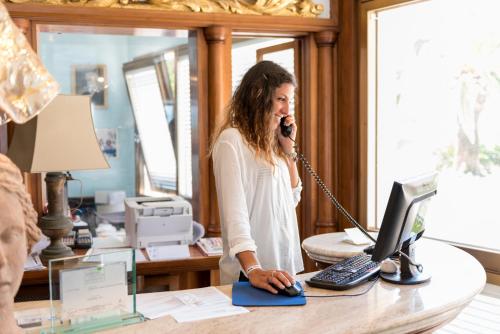 a woman talking on a phone at a desk with a computer at Hotel Ristorante Maga Circe in San Felice Circeo