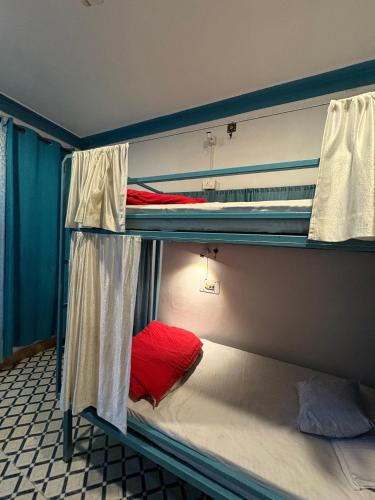 a bedroom with two bunk beds with red sheets at LA SIESTA INDIA MCLEODGANJ in McLeod Ganj