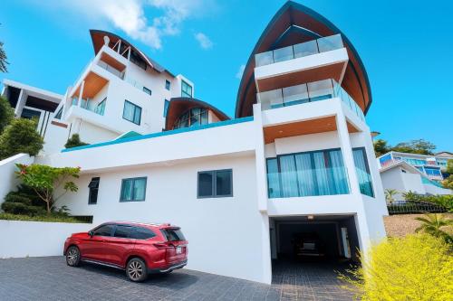 a red car parked in front of a white building at Golden Coconut 4 Bed 6 Bath Luxury Sea View Villa in Chaweng Beach, Koh Samui in Amphoe Koh Samui