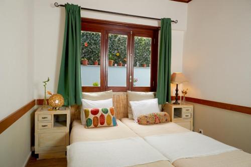 1 dormitorio con 2 camas, cortinas verdes y ventana en Central Garden Saldanha Apartment, en Lisboa