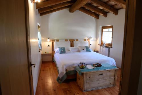 a bedroom with a white bed and a wooden floor at Giardino Sospeso Agriturismo in Valdobbiadene
