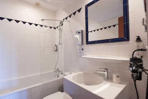 a white bathroom with a sink and a mirror at Hotel Burrhus in Vaison-la-Romaine
