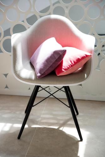 a pink chair with three pillows on it at ABC Hotel in Blankenberge