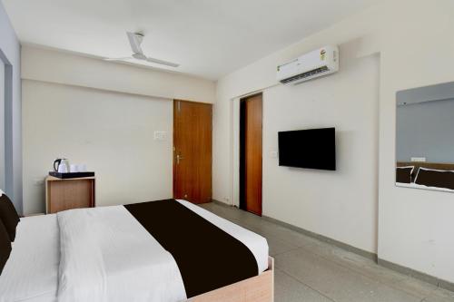 a bedroom with a bed and a tv on the wall at Super Collection O Katraj Bus Stop Formerly Indu Ville in Māngvādi