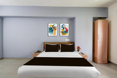 a bedroom with a large bed and two paintings at Super Collection O Katraj Bus Stop Formerly Indu Ville in Māngvādi
