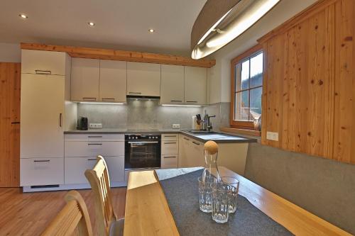 a kitchen with white cabinets and a wooden table at Alpboden in Auffach