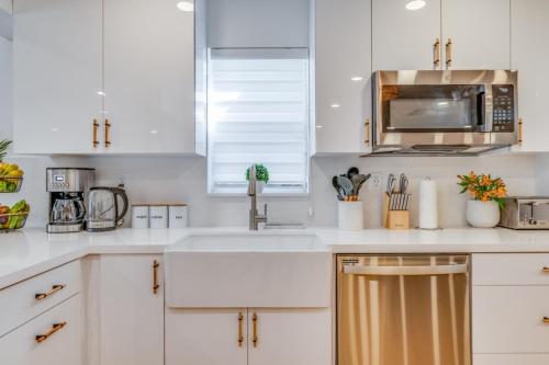 Una cocina blanca con fregadero y microondas. en Fox Garden Luxury Boho Near Downtown & Beach home, en Fort Lauderdale