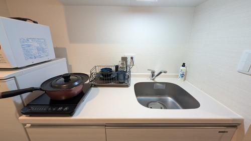 Una encimera de cocina con fregadero y microondas. en M-1 Tokyo Nishirokugo 203, en Tokio