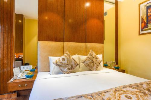 a bedroom with a white bed with a wooden headboard at Stamps Golden Lagoon by Eight Continents - Opposite to Golden Temple in Amritsar