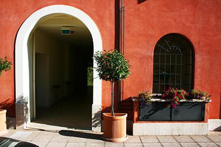 a red building with two potted plants and a window at Residence Bizzoni in Terni