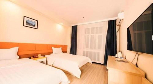 a hotel room with two beds and a flat screen tv at 7 Days Inn Harbin Medical University First Affiliated Hospital in Harbin