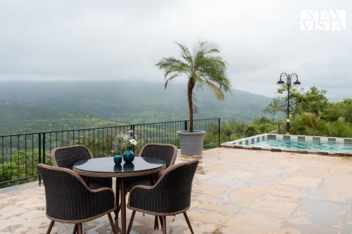 ロナバラにあるStayVista at Apukaa Hills with Karaoke, Poolのヤシの木のあるパティオ(テーブル、椅子付)