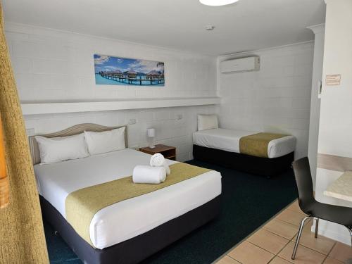a hotel room with two beds and a chair at Cleveland Motor Inn in Cleveland