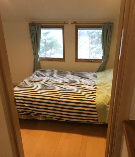 a bedroom with a bed and two windows at Cabin G Lake Saiko 1min, MtFuji View, BBQ, Hammock, fire pit in Narusawa