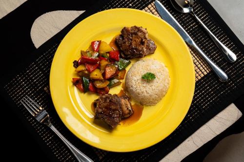 a yellow plate of food with meat and vegetables at Kirindi Paddy Isle in Negombo