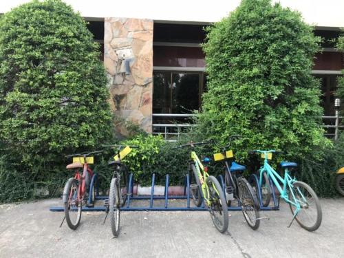 four bikes parked in a rack in front of a building at Hihotel Saraburi in Sara Buri