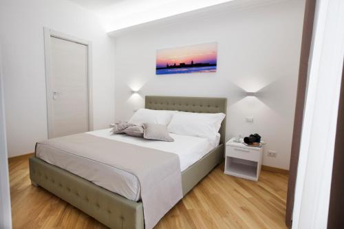 a white bedroom with a bed and a painting on the wall at Appartamenti Trapani In in Trapani