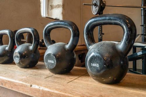 four old black dumbbells sitting on a wooden table at Le gîte de Saint Mathieu, longère pleine de charme au bout du monde ! jacuzzi extérieur vue sur la campagne, salle de billard in Plougonvelin