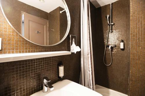 a bathroom with a sink and a mirror and a shower at Hotel Burrhus in Vaison-la-Romaine