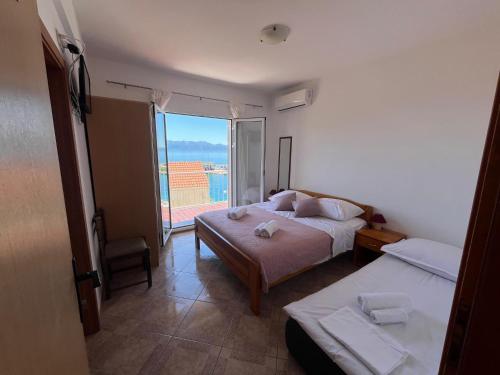 a bedroom with two beds and a large window at Apartments San Giorgio in Sućuraj