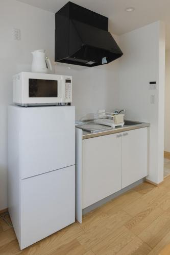 a kitchen with a microwave on top of a refrigerator at 楚々Soso in Miyazu