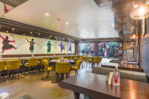 a restaurant with tables and chairs and a wall with a picture of dancers at Stamps Golden Lagoon by Eight Continents - Opposite to Golden Temple in Amritsar