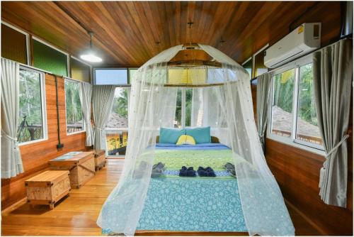 a bedroom with a bed with a mosquito net at Tamsabai Resort in Ban Na Nian