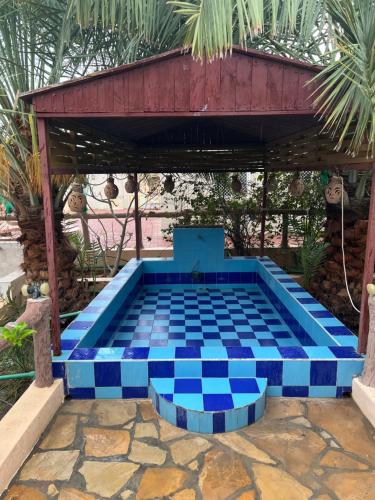 a blue tiled pool in a patio with a building at Maeen Rest House in Ma‘mad